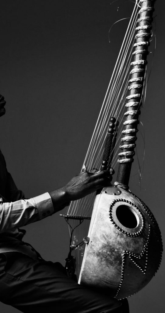 Short story featuring an West African man seated on a stool with his instrument, the kora, in his lap.