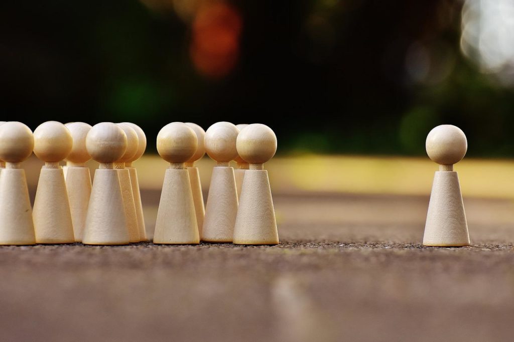 wooden figurines clustered on the left with an isolated figure on the right.