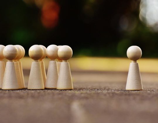 wooden figurines clustered on the left with an isolated figure on the right.